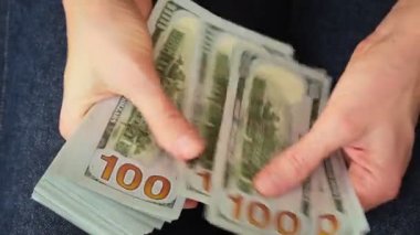 Kadın elleri 100 dolarlık banknotları sayıyor. Aylık maaş, banka kredisi ödemesi, mali yatırım ve kişisel tasarruf kavramı.