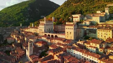 Gün batımında Gubbio, İtalya 'nın nefes kesici hava manzarası. Ortaçağ binaları, Duomo ve Umbria bölgesinde sıcak bir akşam gökyüzü altında parlayan Gotik mimarisi ile dar sokaklar sergileniyor..