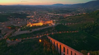 Ortaçağ Spoleto 'sunun dramatik hava manzarası, Umbria' nın geceleri. İtalya 'da şehir ışıkları altında parıldayan Ponte delle Torri su kemeri ve Rocca Albornoziana kalesi yer alıyor..