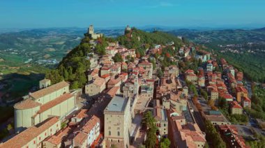San Marino 'nun görkemli üç kulesinin, tarihi ortaçağ mimarisinin ve güzel bir tepe manzarasının yer aldığı eski bir şehrin insansız hava aracı görüntüsü..