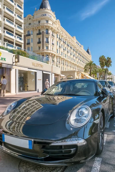Cannes, Fransa - 21 Eylül 2024: Carlton Hotel 'in önüne park edilmiş siyah lüks bir spor araba ve Cote d Azur' daki lüks butikler..