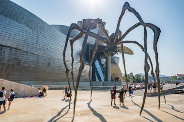 Bilbao, İspanya - 10 Ağustos 2024: Güneşli bir yaz gününde Bilbao Titanyum Guggenheim Müzesi 'nin önünde duran Louise Bourgeois tarafından Maman başlıklı dev bronz örümcek heykeli.