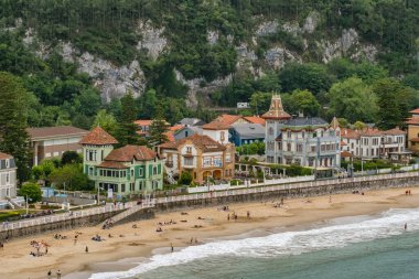Ribadesella, İspanya. Altın kum, turist ve turistlerin yer aldığı Santa Marina sahili manzarası. Gezintiye çıkan tarihi İndiano tarzı villalar yemyeşil bir dağ zeminine karşı..
