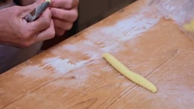 Bari, Puglia, İtalya 'da bir sokakta geleneksel Orecchiette makarnası yapan bir kadını yakından çek. Tarihi kentteki ahşap bir masada el yapımı makarnanın özgün sanatını yakalar..