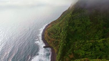 Portekiz, Azores 'te bulutlu ve sisli havada Miradouro da Ponta do Sossego' dan görülen Sao Miguel adasının yüksek yeşil uçurumları. Dramatik Atlantik adası doğası olan manzaralı kıyı manzarası..