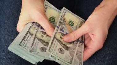 Kadın elleri 100 dolarlık banknotları sayıyor. Aylık maaş, banka kredisi ödemesi, mali yatırım ve kişisel tasarruf kavramı.