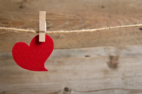 Red fabric heart hanging on the clothesline. On old wood backgro — Stock Photo, Image