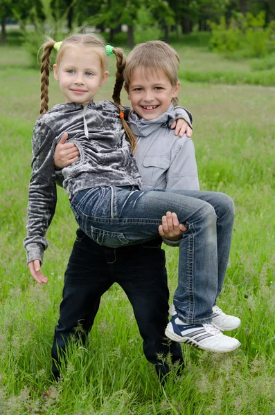 Silná a roztomilý chlapec zvedl a drží dívku — Stock fotografie