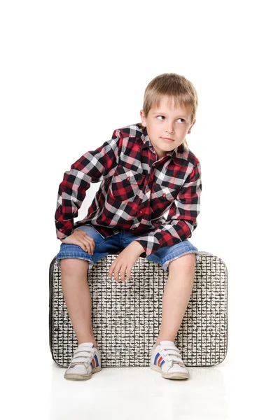 Niño sentado en la maleta aislado sobre fondo blanco —  Fotos de Stock