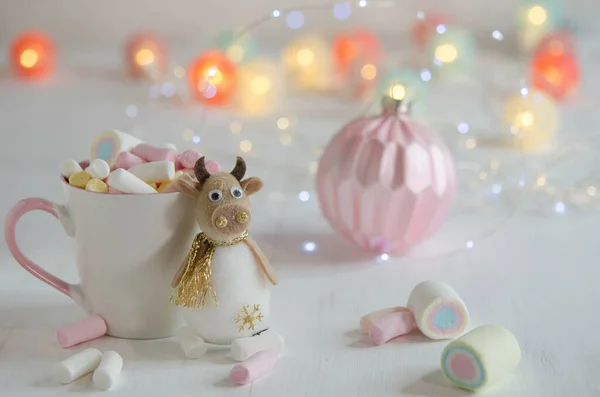 Witte Beker Met Marshmallows Een Speelgoedstier Een Wazige Achtergrond Kerstversiering — Stockfoto