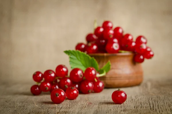 Grosella roja en plato de madera sobre la mesa — Foto de Stock