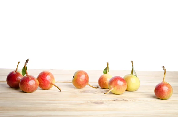 Many small round pears with leaves on wooden table — Stock Photo, Image