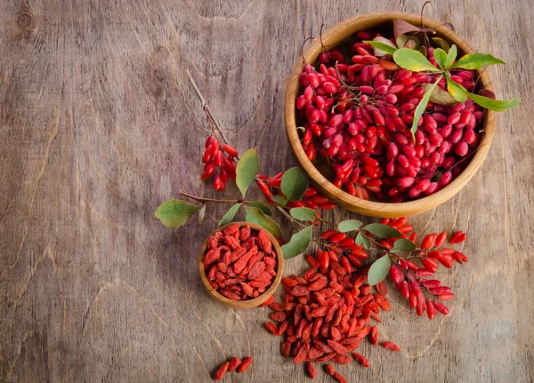 Bayas de Barberry y goji secas en dos cuencos sobre fondo de madera — Foto de Stock