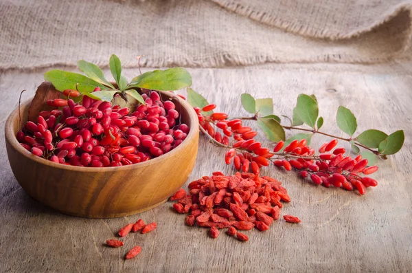 Barberry με φύλλα και η ξηρά goji μούρα στο ξύλινο υπόβαθρο — Φωτογραφία Αρχείου