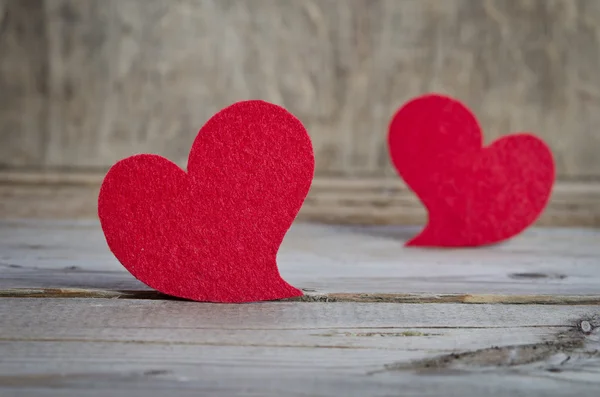 Dos corazones de tela roja de pie sobre una tabla de madera. Sobre madera vieja ba —  Fotos de Stock