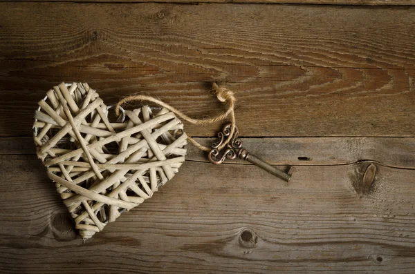 Wicker heart handmade with the key lying on a wooden base . top — Stock Photo, Image