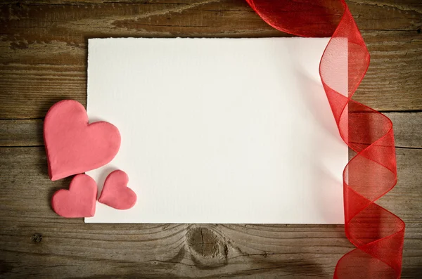 Pedazo de papel acostado con corazones y cinta en un backgrou de madera —  Fotos de Stock