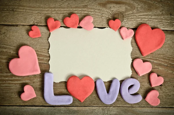 Palabra Composición de amor en la superficie del tablero de madera y muchos corazones — Foto de Stock
