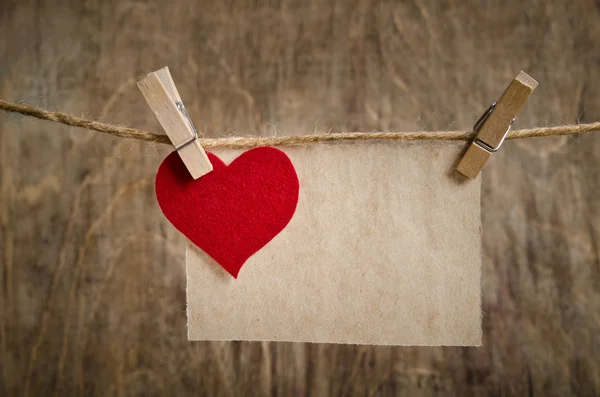 Coeur en tissu rouge avec feuille de papier accrochée à la corde à linge . — Photo