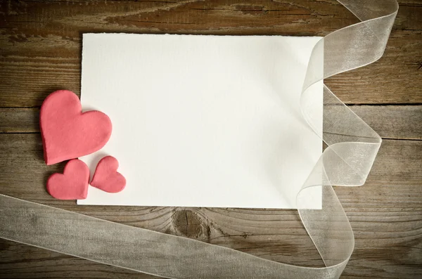 Pedazo de papel acostado con corazones y cinta en un backgrou de madera —  Fotos de Stock