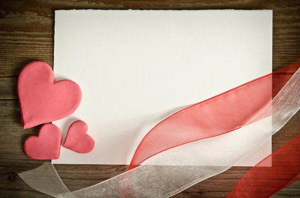 El pedazo de papel acostado con corazones y cintas en un bac de madera — Foto de Stock