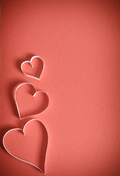 Three hearts from white paper are lying on a red background Stock Picture
