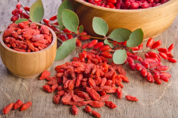 Bagas de baga e goji secas em tigelas em fundo de madeira — Fotografia de Stock