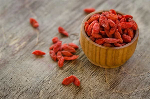 Goji berries in bowl and on the table isolated on wooden backgro — Stock Photo, Image