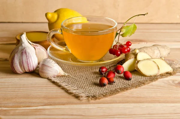 Чашка чая, ломтики имбиря, меда, ягод шиповника и вибурнума — стоковое фото