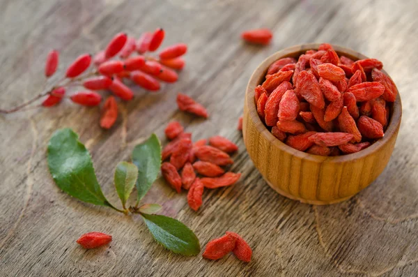 Bayas y bayas de goji aisladas sobre fondo de madera —  Fotos de Stock