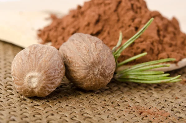 Nutmeg with a sprig of rosemary and cacao powder in the wooden s — Stock Photo, Image