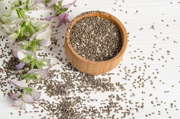 Semilla de chía saludable súper alimento con flor sobre fondo de madera blanca — Foto de Stock