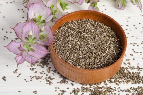 Semilla de chía saludable súper alimento con flor sobre fondo de madera blanca — Foto de Stock