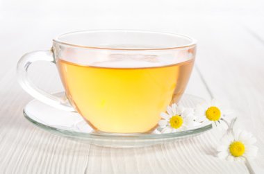 Ahşap masa üzerinde tıbbi papatya çayı fincan