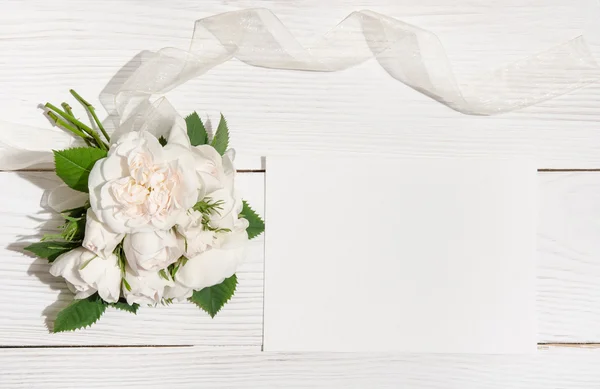 Bunch of white roses on white table with empty card for you text — Stock Photo, Image
