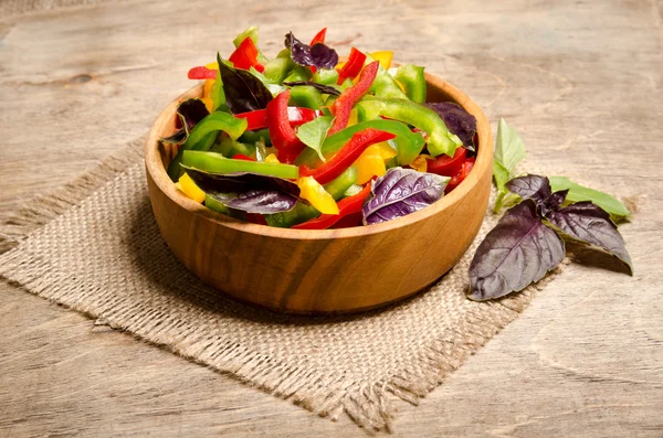 Ensalada de pimiento y albahaca en un tazón de madera sobre tabla de madera —  Fotos de Stock