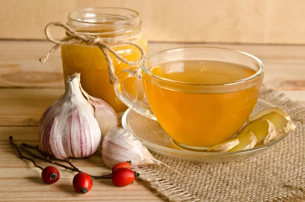 Cup of tea and twigs near wild rose on a wooden background — Stock Photo, Image