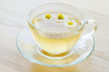 Ahşap masa üzerinde tıbbi papatya çayı fincan