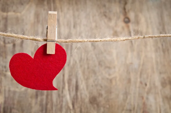 Coeur en tissu rouge accroché à la corde à linge. Sur vieux backgro en bois — Photo