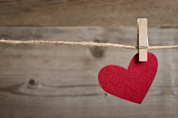 Rode stof hart opknoping op de waslijn. Op oude houten backgro — Stockfoto