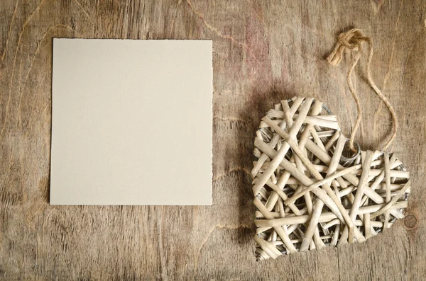 Weidenherz handgefertigt liegend auf einem Holzsockel mit einem Blatt Pap — Stockfoto