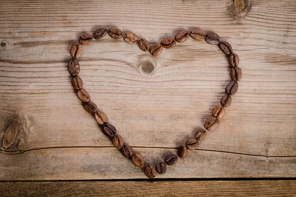 Frame-hart van koffiebonen op houten tafel — Stockfoto