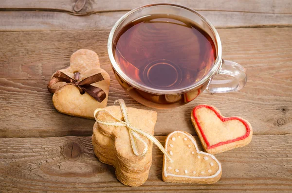 Galletas-corazones relacionados y una taza de té en una mesa de madera — Foto de Stock