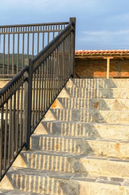 Metal çit ve kayanın üzerindeki gölge gökyüzüne doğru ilerliyor.