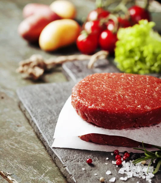 Raw Ground beef meat Burger steak cutlets with seasoning and veg — Stock Photo, Image