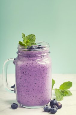 Açık yeşil arka planı üzerinde Blueberry smoothie