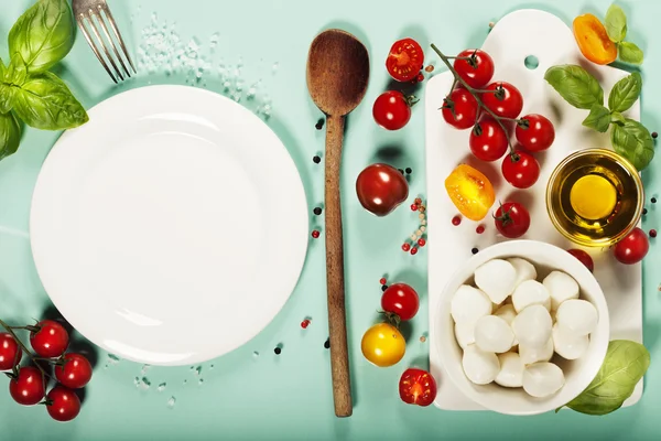 Tablero de cerámica blanca e ingredientes de ensalada sobre blu claro — Foto de Stock