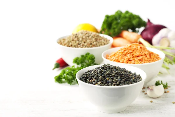 Bowls of assorted dried lentils with vegetables — Stock Photo, Image