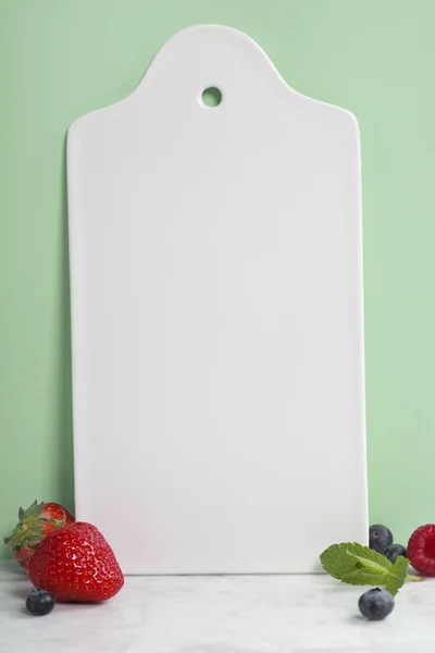 White ceramic serving board and berry over light blue background — Stock Photo, Image