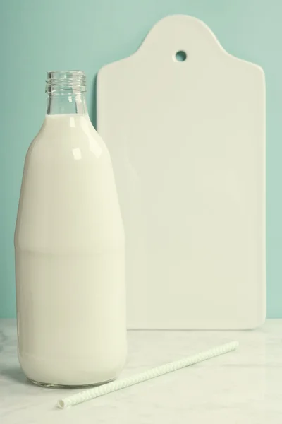 Eine Flasche rustikale Milch und Papierstroh auf weißem Marmortisch — Stockfoto